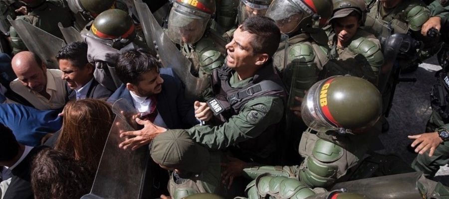 Armando Armas rodeado de funcionarios de seguridad con cascos, escudos y equipos antidisturbios.