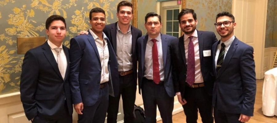 Armando Armas posando junto a cinco hombres vestidos de traje durante un encuentro grupal.