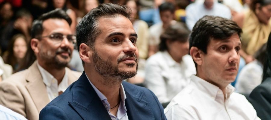 Armando Armas sentado con traje azul entre los asistentes al evento de María Corina Machado en Oslo.