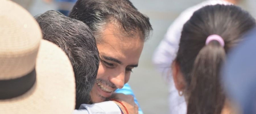 Armando Armas sonriendo mientras abraza a una persona durante una actividad al aire libre.