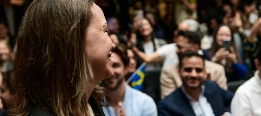 Armando Armas sentado entre los asistentes al evento de María Corina Machado en Oslo, Noruega, mientras el público aplaude.