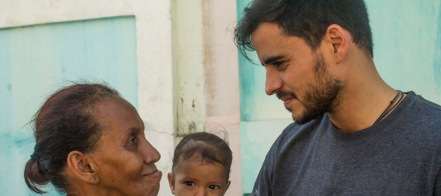Armando Armas conversando con una mujer que sostiene a un bebé en brazos.