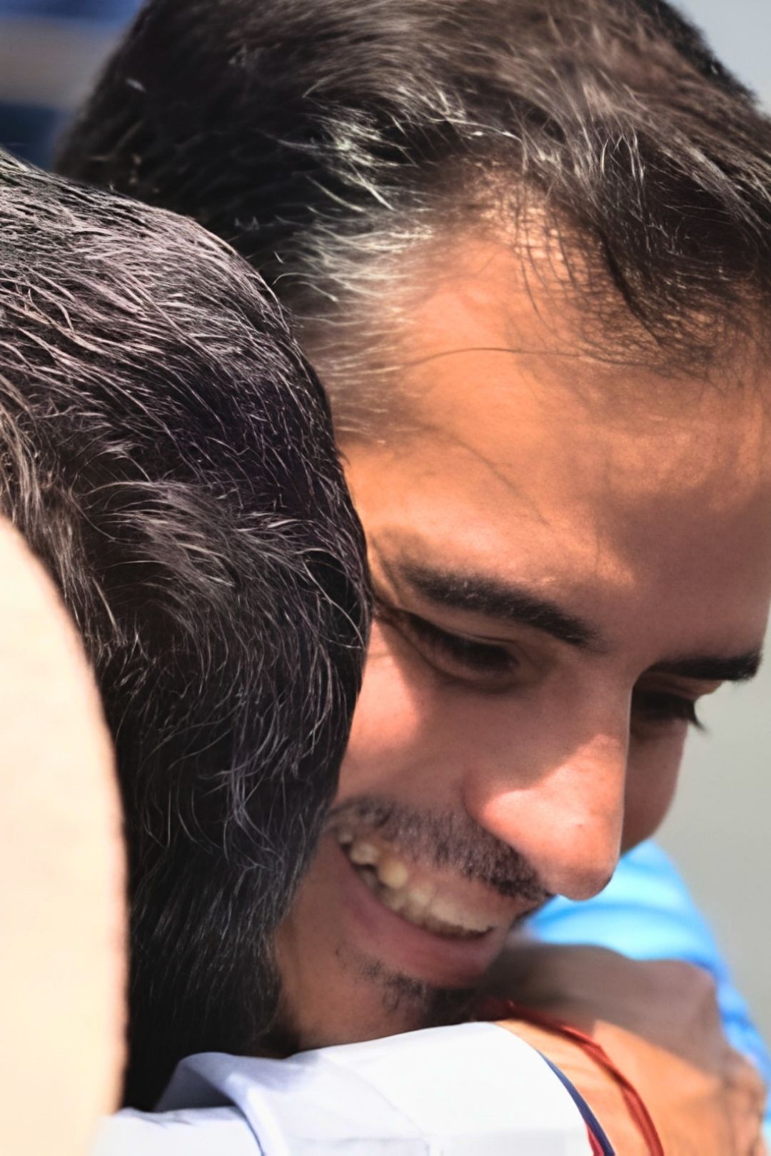 Armando Armas sonriendo mientras abraza a una persona durante una actividad al aire libre. (Vertical)